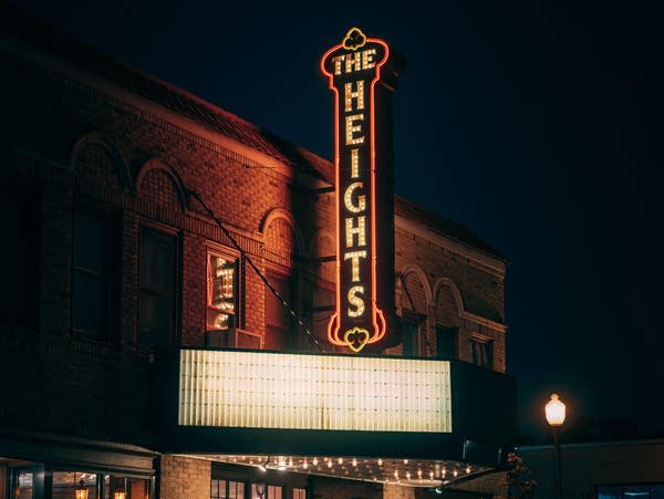 Nighttime view of a lit-up theater marquis and sign.