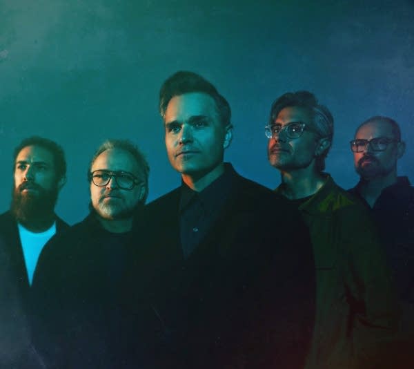 Five men stand together for a studio portrait