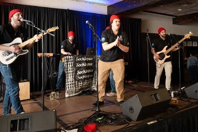 Four men wearing red beanies performing