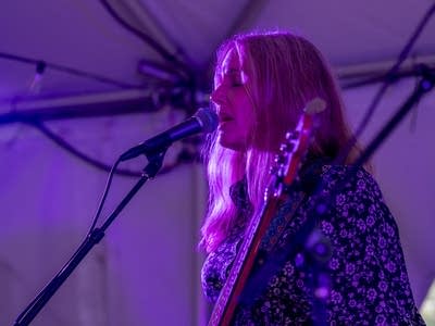 a woman playing bass and singing on stage