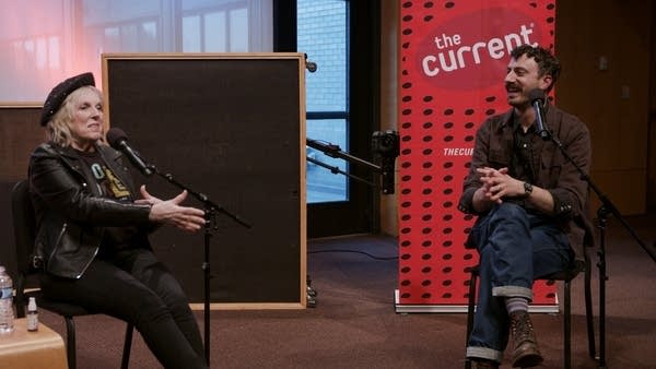 Two people have a conversation in a small auditorium