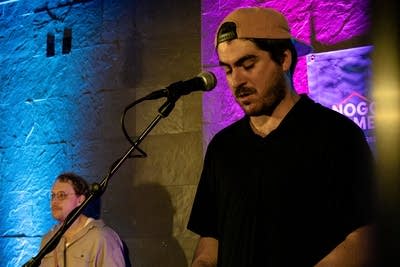 Two musicians perform onstage in a music venue