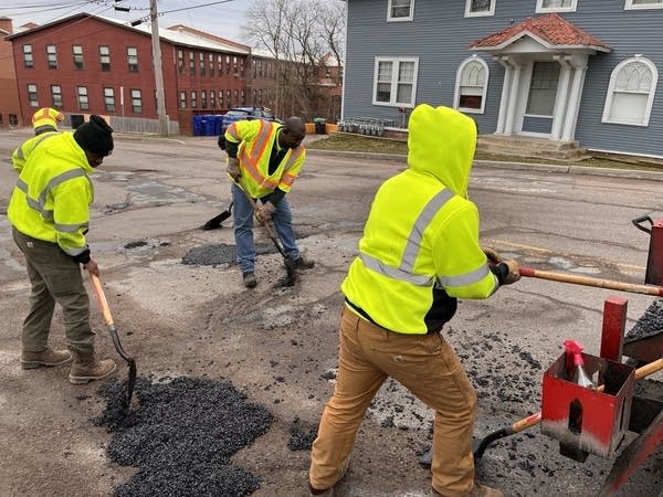 Crew members with the Winooski, Vt. department of public works shovel asphalt into potholes on East Spring Street.