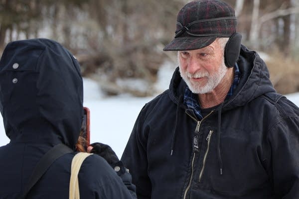 Two people talk outside in the snow.