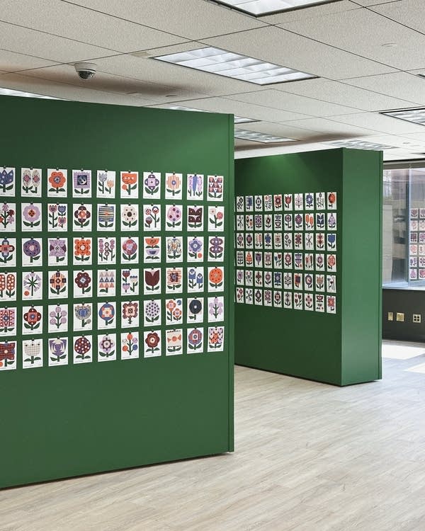 Postcards are displayed in a gallery on green painted walls.