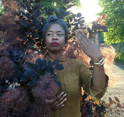 A%20person%20posing%20for%20a%20picture%20near%20a%20bush.