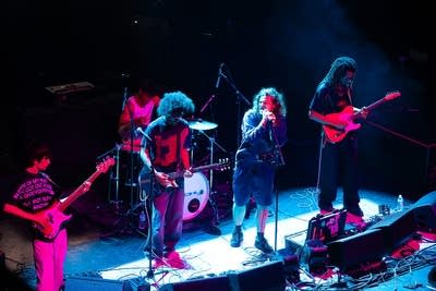 A five-piece band performing onstage in a large music venue