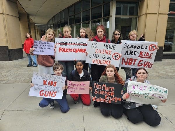 A group of students line up to pose for a photo with their protest signs.
