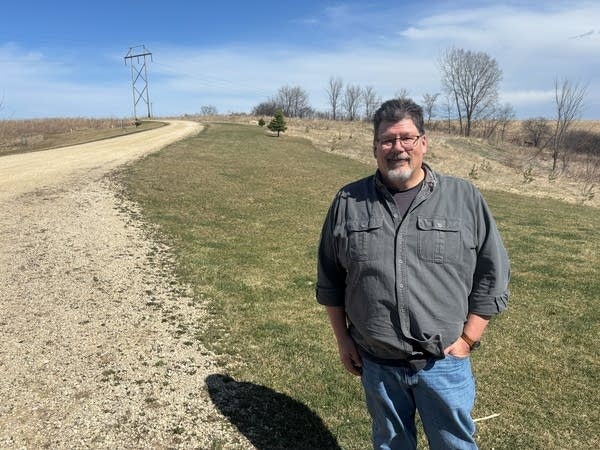 A man stands at the foot of his driveway.