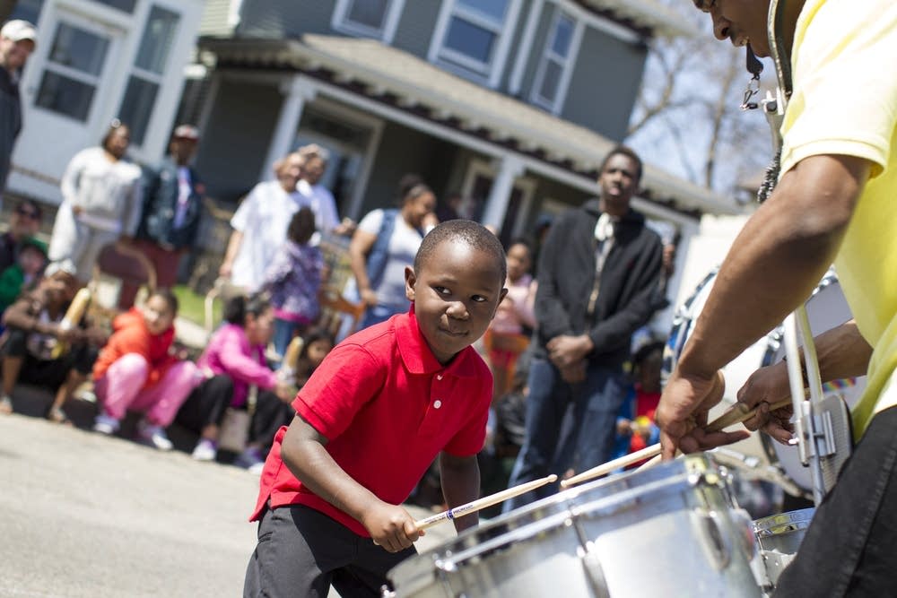 A young drummer plays with a drill and dance team.