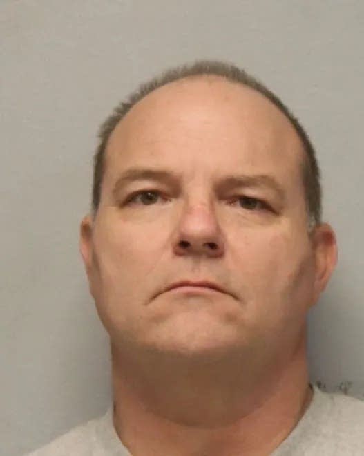 A booking photo of a man with balding short hair.