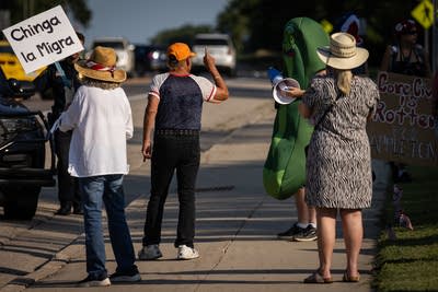 A man gestures at a protester in a pickle costume