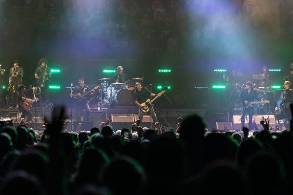 A band performing onstage during a concert in an arena