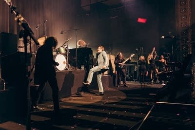 A band performing onstage in a large music venue