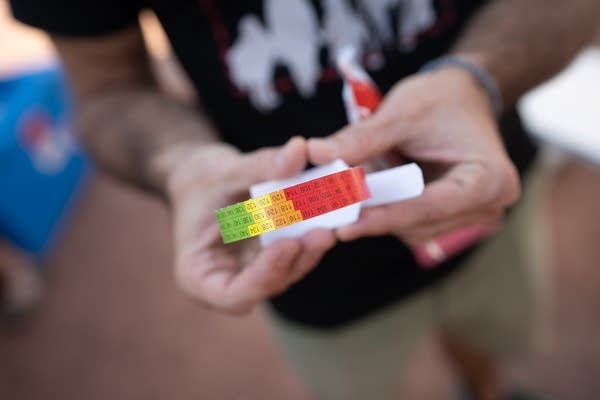 A Doctors Without Borders guide holds up a card MUAC band.