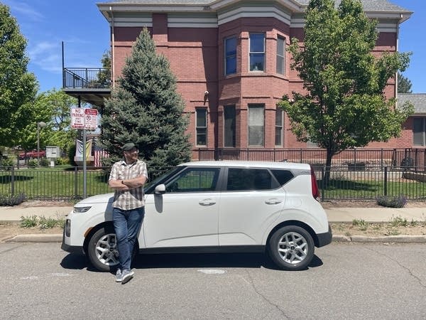 Photo of Andrew leaning against his rented Kia Soul on sunny day