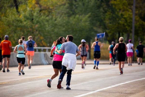 A man kisses a woman as she runs next to him.