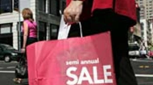 A shopper carries a bag advertising a sale.