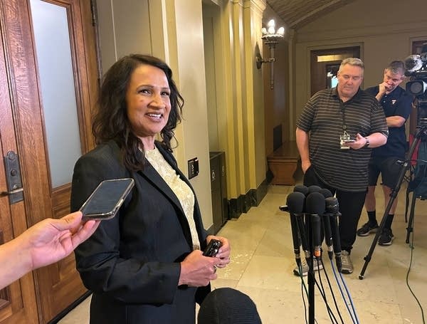 A woman speaks with reporters