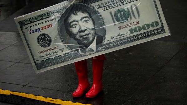 A supporter carries a sign representing Democratic presidential candidate Andrew Yang's plan for a $1000 monthly universal basic income during a rally in Washington Square Park, May 14, 2019 in New York City. One of Yangs major campaign promises is a universal basic income of $1,000 every month for every American 18 years and older.