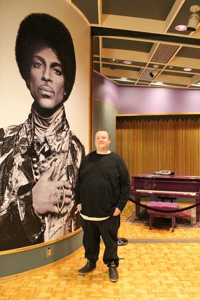 Sean McPherson stands next to a wall-size photo of Prince