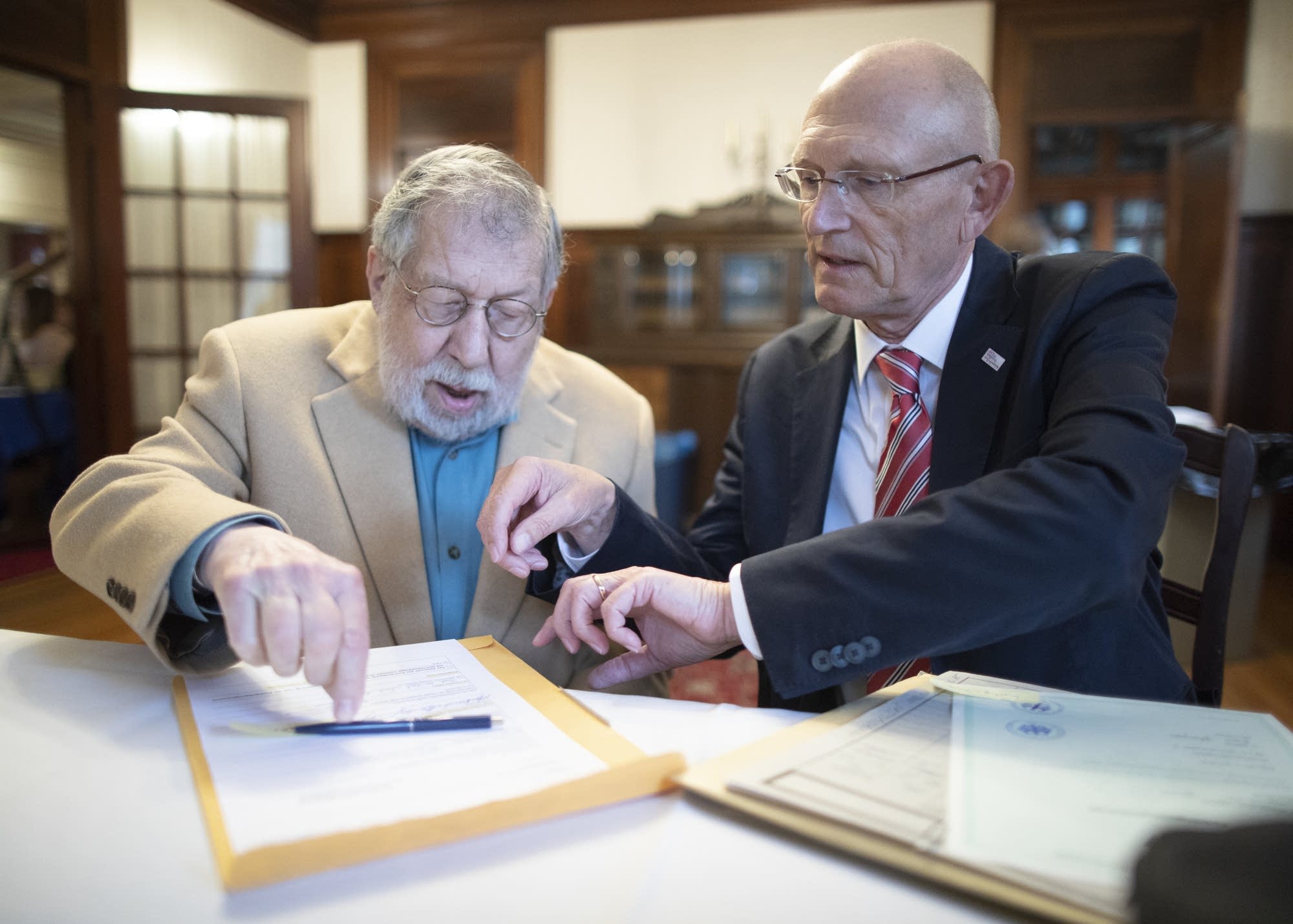 Fred Amram (left) signs citizenship documents.