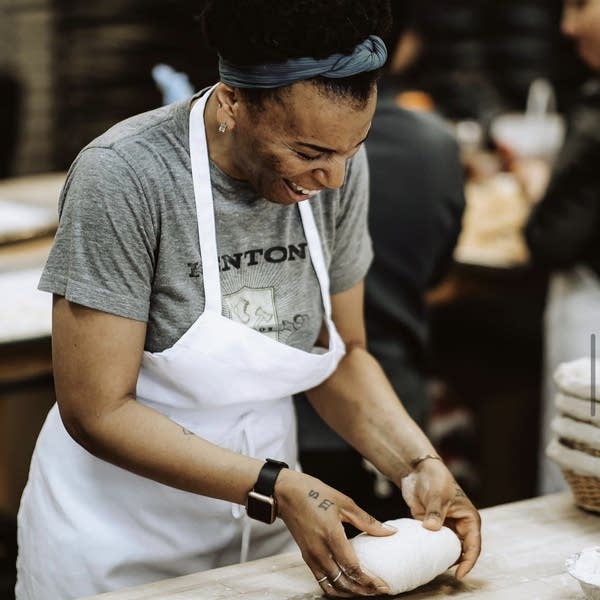 A woman holds dough on a table