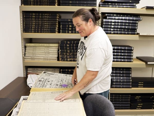 a woman in a white shirt looks at a book on a table
