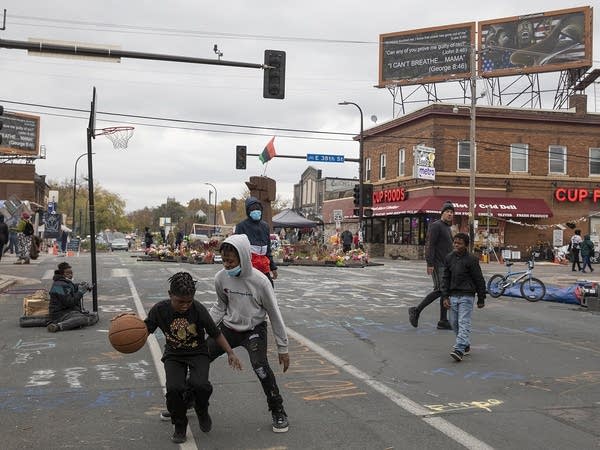 Kids play basketball in the street. 