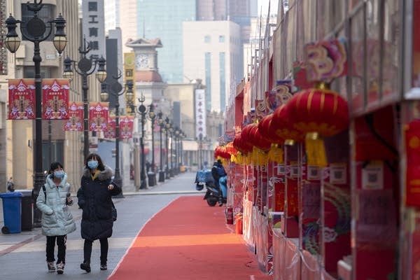 People wearing masks walk on an empty street in downtown Tianjin, China.