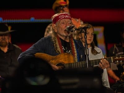 Willie Nelson strums an acoustic guitar