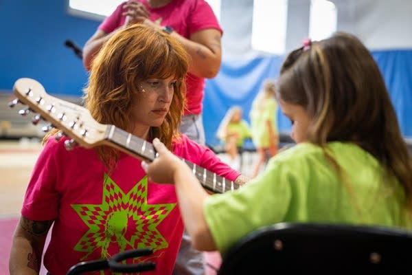 A person helps a camper with their guitar