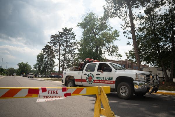 A white pickup truck is parked just behind a wooden barricade on a street.