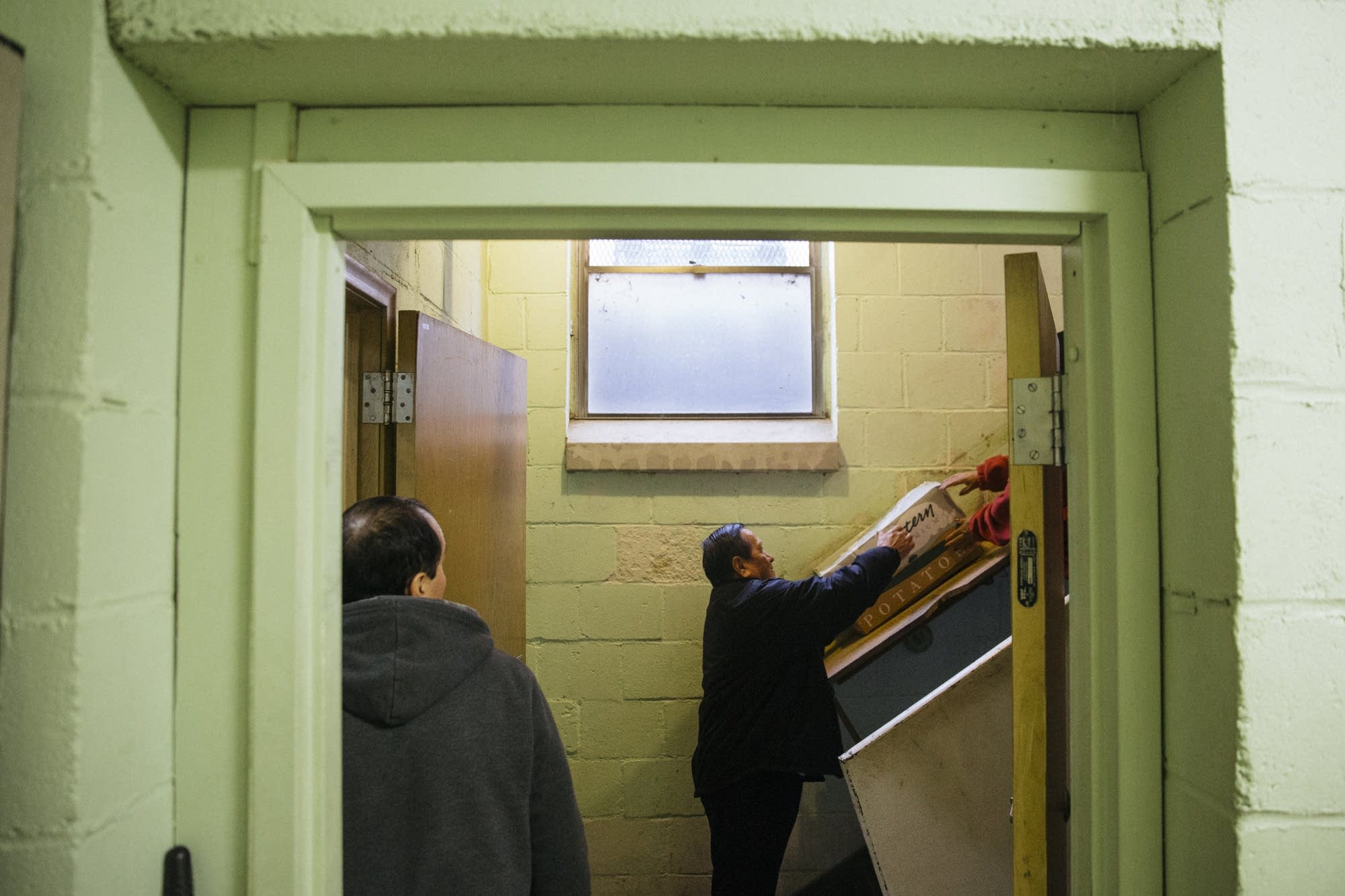 Volunteers slide food donations into the basement.