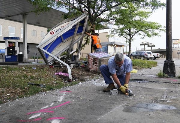 People clean up debris at the site of a crash.