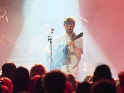 A man plays a guitar and sings into a microphone.