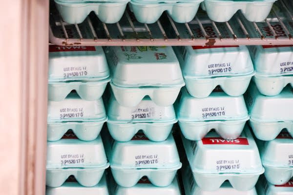 A fridge shelf full of cartons of eggs.