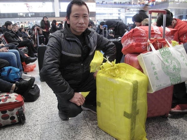 A man stoops in front of his luggages.