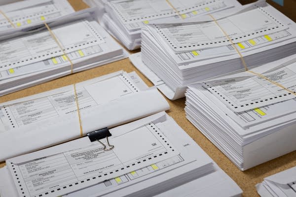 Stacks of collated mail-in ballots packets are being prepared