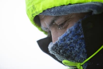 Ice crystals collect on Herlbelto Rosendo's face as he snowblows.