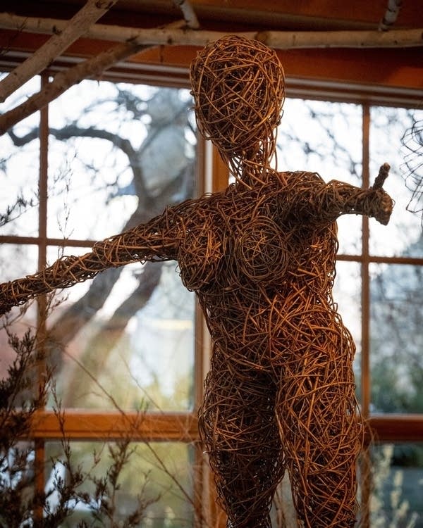 A sculpture of a woman's body made out of wooden twigs.