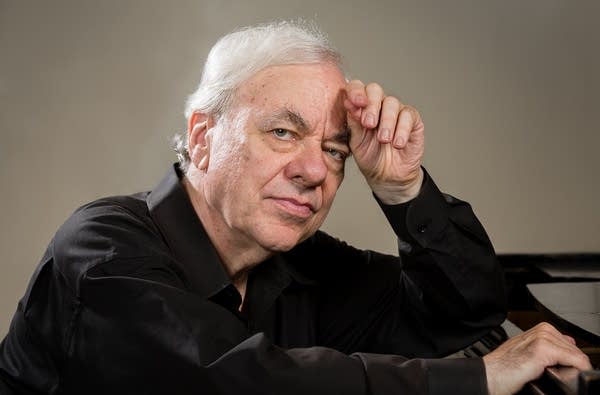 A man leans against a piano