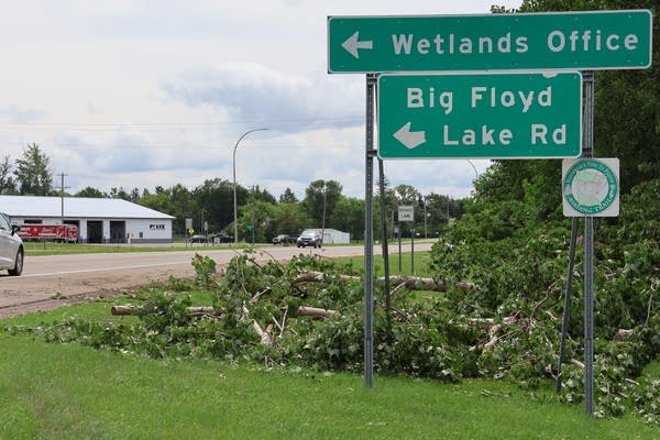 Fallen tree limbs lay next to a road sign for "Wetlands Office" and "Big Floyd Lake Rd."