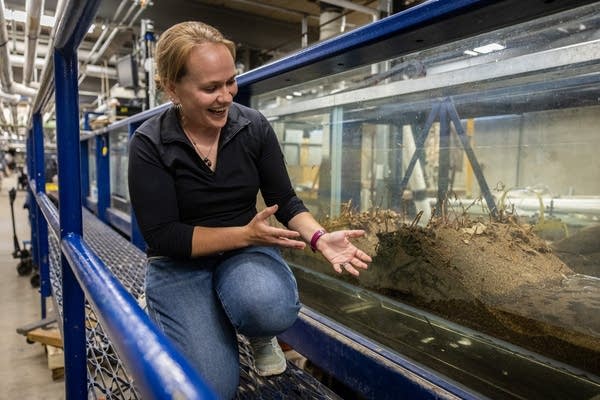 A woman kneels next to a research flume