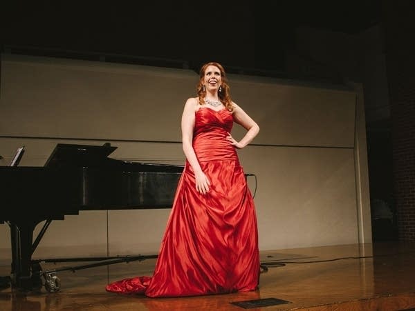 a woman in a red dress stands on stage