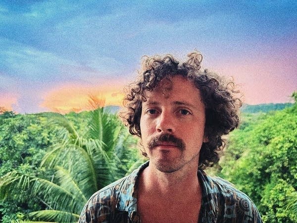 A man standing above a tropical landscape
