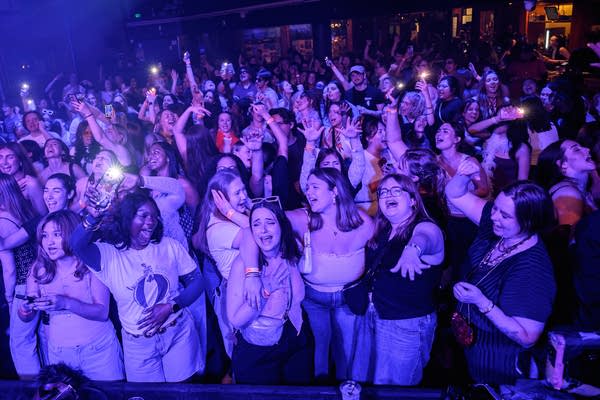 People dance under purple lights