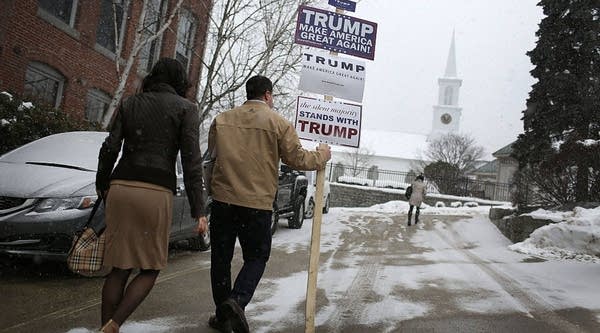 A volunteer carries a campaign sign supporting Republican presidential candiate Donald Trump as he leaves the Newmarket Trump campaign headquarters on February 8, 2016 in New Hampshire. 