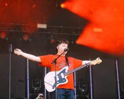 A musician sings and plays guitar on a large outdoor stage