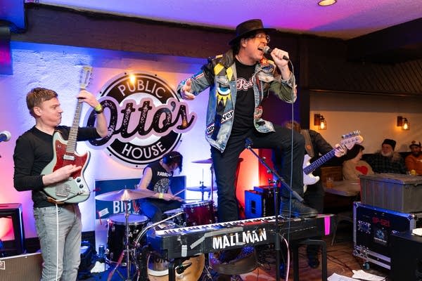Man singing microphone and band behind